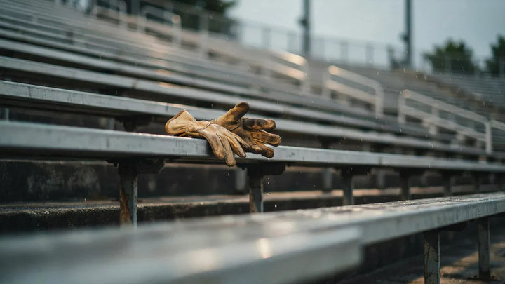Worn work gloves left on empty metal stadium bleachers in light rain