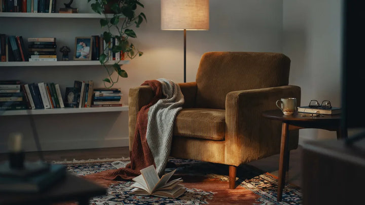 A worn corduroy armchair in soft evening lamplight — memorial song for a late husband