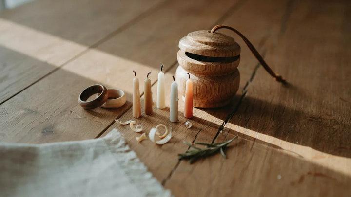 A carved wooden keepsake with two wooden rings and five small candles on an oak table in warm light