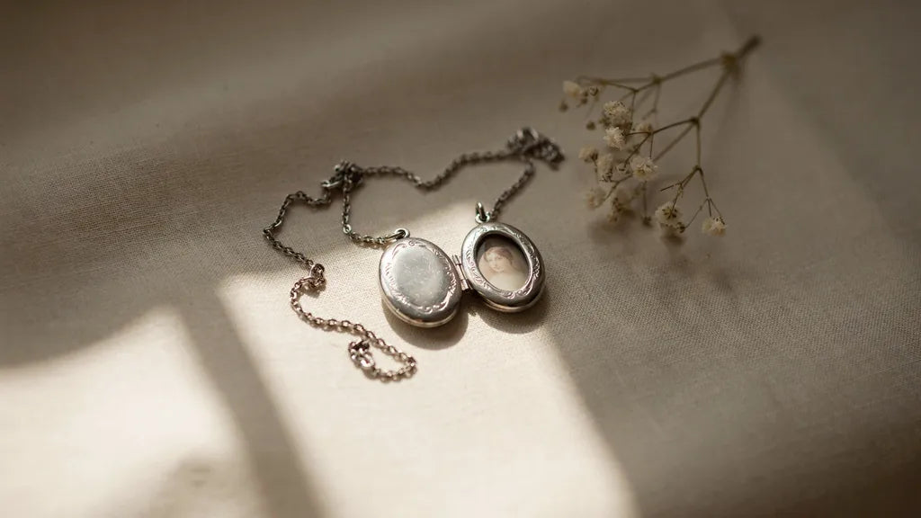 Two small silver lockets with intertwined chains resting on cream linen in soft light