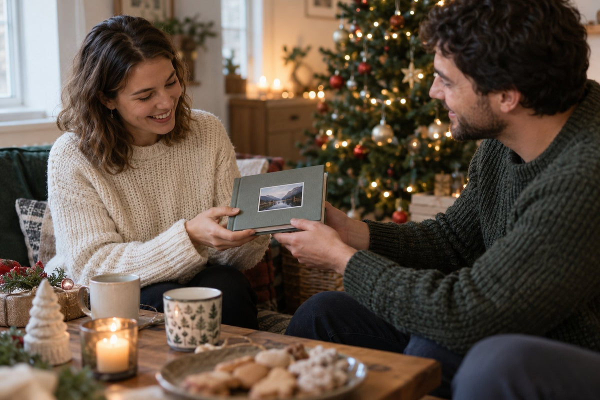 Two adults sharing a photograph beside a Christmas tree.