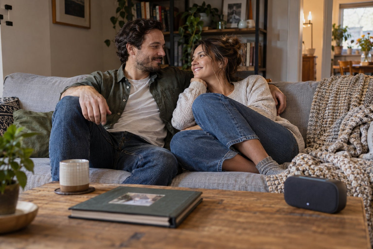 An adult couple listening beside a small speaker at home.