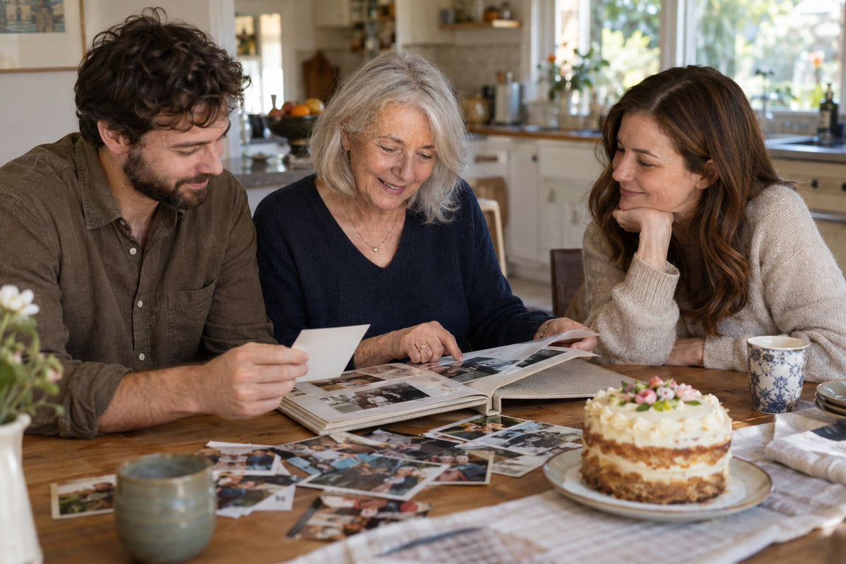 A woman and adult relatives sharing family photographs beside a birthday cake.