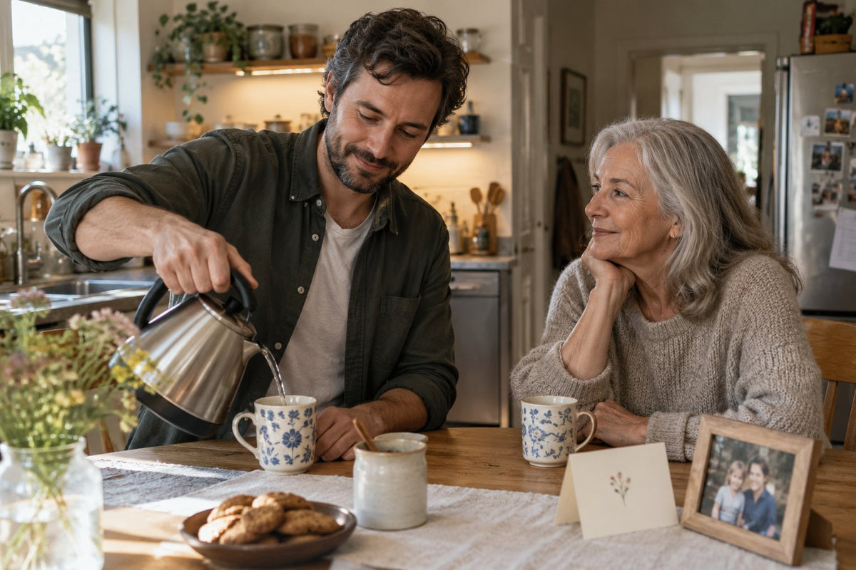 An adult son pouring tea for his mother in a kitchen.