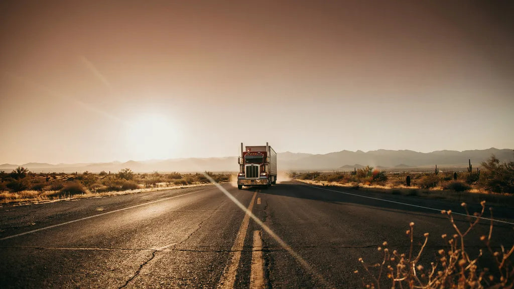 A red semi truck on an open highway at golden hour — custom songs for truckers | Songbond