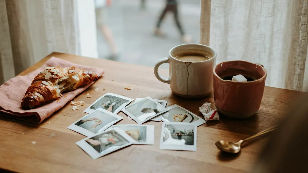 Two coffee mugs and scattered photos on a cafe table — custom songs for a best friend | Songbond