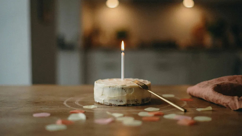 A small cake with one lit candle — custom birthday songs | Songbond