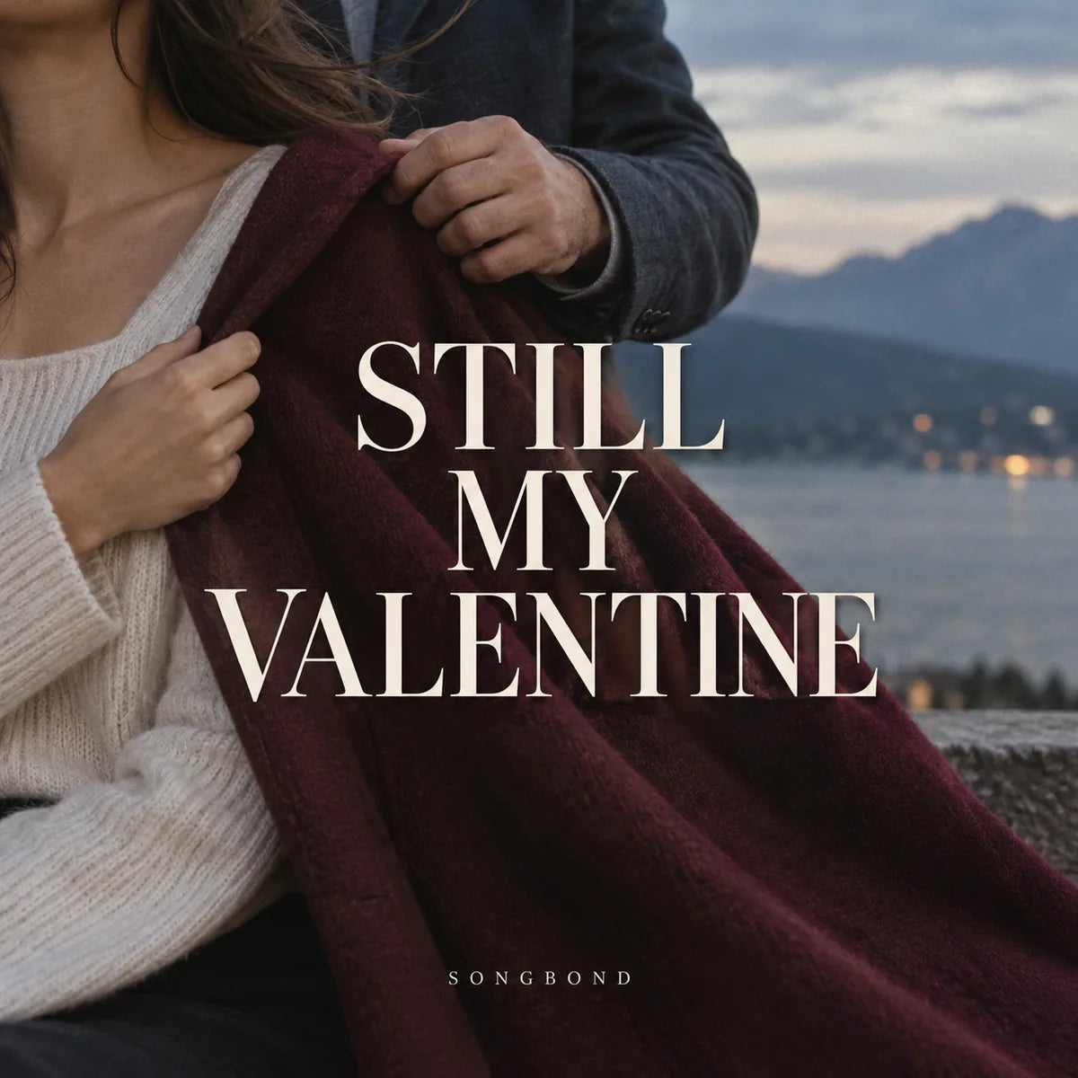 Music cover for Still My Valentine by Songbond, with a husband's hand placing a burgundy coat over his wife's shoulders against a cool lakeside background and cream type.